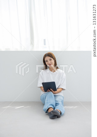 Smiling young woman holding a tablet in a bright room Smiling young woman holding a tablet in a bright room 131631273