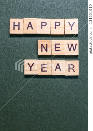 Wooden letter tiles spelling Happy New Year arranged neatly on a textured green background Wooden letter tiles spelling Happy New Year arranged neatly on a textured green background 131631910