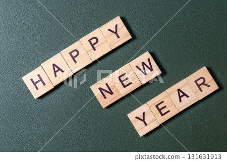 Wooden letter tiles spelling Happy New Year arranged neatly on a textured green background Wooden letter tiles spelling Happy New Year arranged neatly on a textured green background 131631913