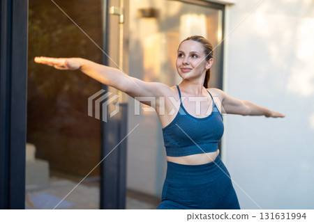 Young woman doing yoga and standing a warrior pose 131631994