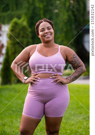 Happy woman in pink standing at the lawn and looking positive 131632142