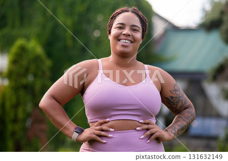 Happy woman in pink standing at the lawn and looking positive 131632149