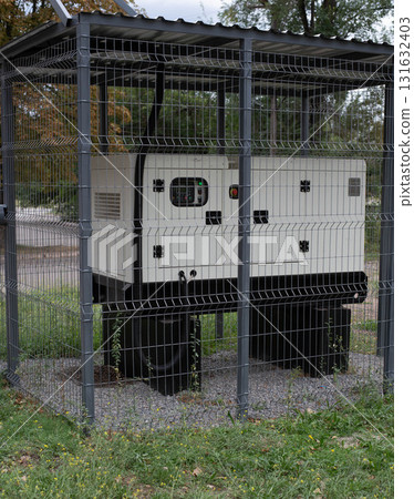 Installation of a large industrial fuel-fired generator on a green lawn. A mobile power source, backup equipment for power plants. Installation of a large industrial fuel-fired generator on a green lawn. A mobile power source, backup equipment for power plants. 131632403