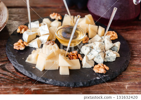 Cheese plate with honey and nuts on a wooden table. Cheese plate with honey and nuts on a wooden table. 131632420
