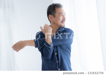 Middle-aged man stretching by the window in the morning Middle-aged man stretching by the window in the morning 131632734