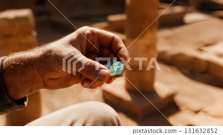 A person's hand holding a piece of mosaic. Mosaic, ancient art, history, heritage, archaeology A person's hand holding a piece of mosaic. Mosaic, ancient art, history, heritage, archaeology 131632852