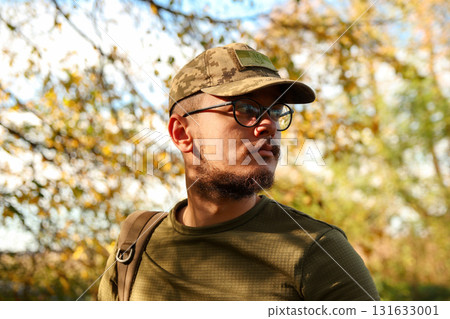 portrait of a Ukrainian soldier outside, featuring a determined man in uniform with a cap adorned with the coat of arms. Autumn nature background 131633001