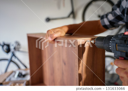 Carpenter using drill to drilling wooden board during furniture assembly 131633066