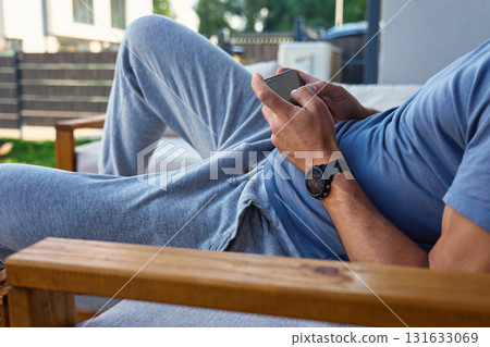 Man relaxing outdoors with smartphone in hands Man relaxing outdoors with smartphone in hands 131633069