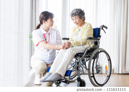 Elderly person in a wheelchair and a young female caregiver 131633315