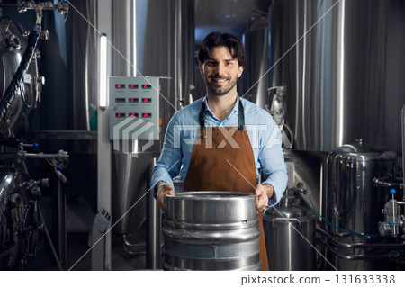 Brewer man is diligently carrying a large metal barrel 131633338
