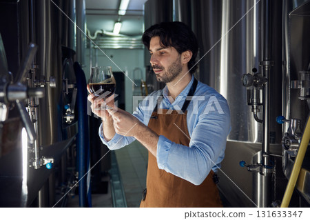 A man is taking a moment to smell a glass of beer in a brewery 131633347