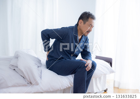 Middle-aged man resting his waist on the bed Middle-aged man resting his waist on the bed 131633825