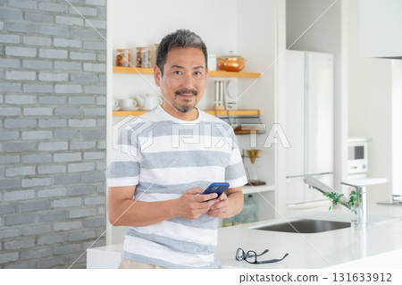 Middle-aged man using smartphone in the kitchen 131633912