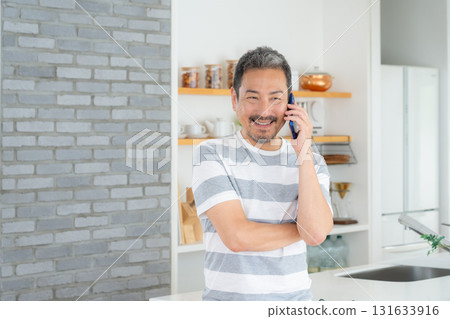Middle-aged man using smartphone in the kitchen Middle-aged man using smartphone in the kitchen 131633916