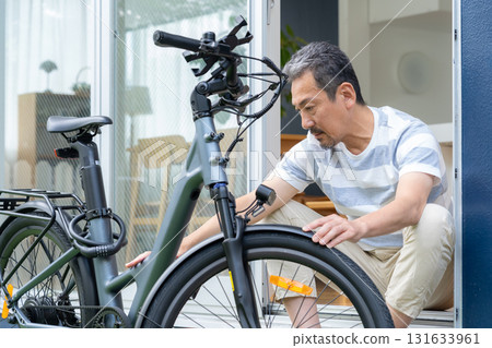 一名中年男子在花園裡保養電動自行車 131633961