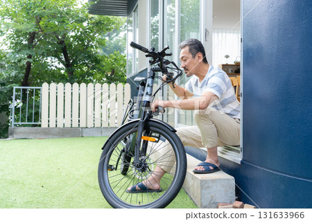一名中年男子在花園裡保養電動自行車 131633966