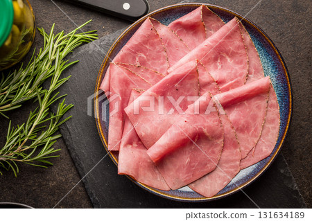 Sliced beef pastrami on plate on black table. Top view. 131634189