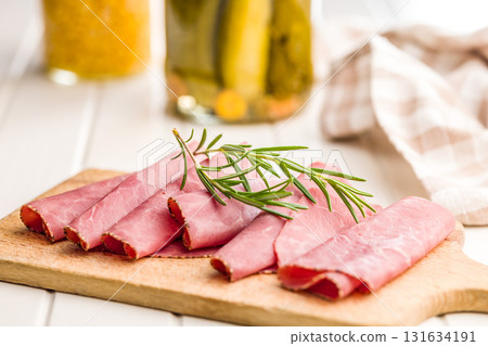 Sliced beef pastrami on cutting board on white table. 131634191