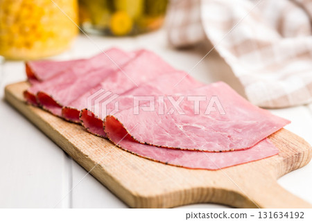 Sliced beef pastrami on cutting board on white table. 131634192