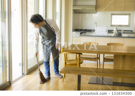 A man cleaning the living room with a broom 131634300