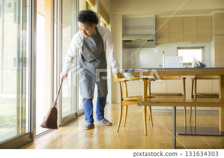 一個男人用掃帚打掃客廳 131634303