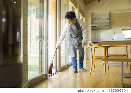 一個男人用掃帚打掃客廳 一個男人用掃帚打掃客廳 131634304