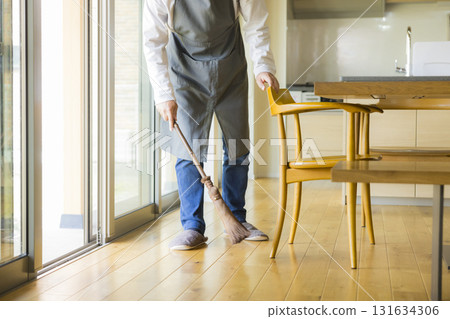 A man cleaning the living room with a broom A man cleaning the living room with a broom 131634306