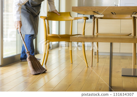 A man cleaning the living room with a broom 131634307