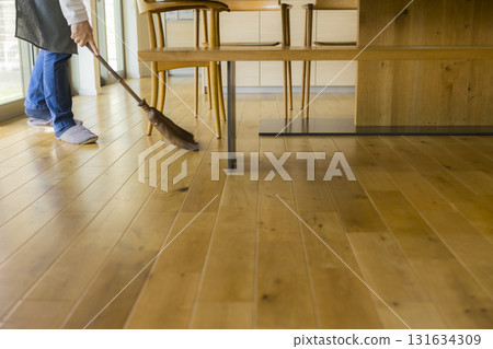 A man cleaning the living room with a broom 131634309