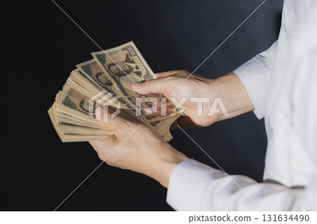 一名身穿工作服的男子正在數一萬日元鈔票 一名身穿工作服的男子正在數一萬日元鈔票 131634490