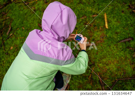 Little girl documenting forest environment with a toy camera during outdoor exploration in Czech woodland. Early childhood education, nature study and environmental awareness through play. 131634647