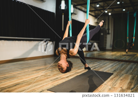 Young woman focusing on strength, balance, and flexibility in a modern yoga studio 131634821