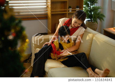 Mother and daughter using digital tablet together in a festive home environment during Christmas time 131634841