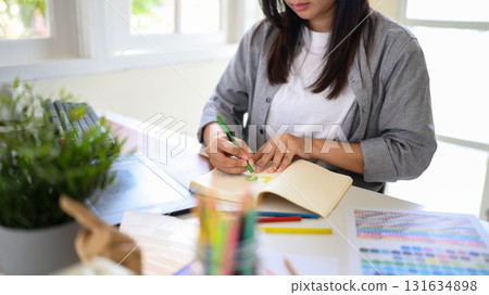 Creative graphic designer sketching logo ideas with colored pencils in a notebook 131634898