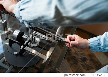 man sharpens a chef's knife with a sharpening system in the kitchen. Manual High Precision Guided Sharpening Equipment for knives 131635212