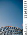 Vertical screen: curved metal beams creating robust and intricate framework rise against clear blue sky, highlighting elegance of industrial design and contemporary architecture. Modern architecture 131635256