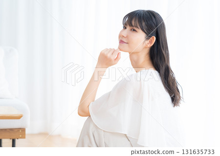 Middle-aged woman doing skin care in the living room Middle-aged woman doing skin care in the living room 131635733
