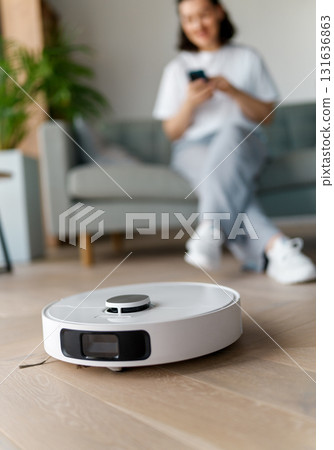 White robotic vacuum cleaner on wooden floor 131636863