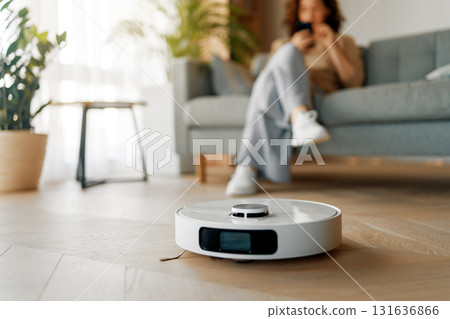 White robotic vacuum cleaner on wooden floor 131636866