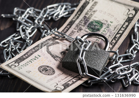 Five dollars are attached with a metal chain and a block Five dollars are attached with a metal chain and a block 131636990