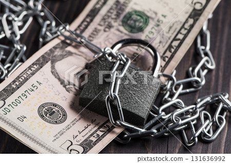Five dollars are attached with a metal chain and a block Five dollars are attached with a metal chain and a block 131636992