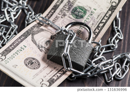 The dollar bill, chain and lock create a visual metaphor The dollar bill, chain and lock create a visual metaphor 131636996