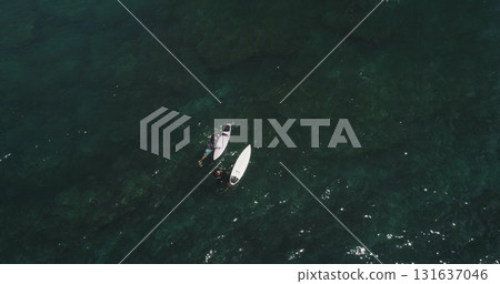 Aerial drone of two surfers waiting for waves in the clear green water of Dreamland Beach, Bali, Indonesia, a popular surfing destination Aerial drone of two surfers waiting for waves in the clear green water of Dreamland Beach, Bali, Indonesia, a popular surfing destination 131637046