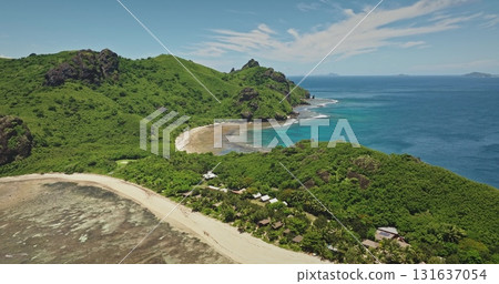 Fiji, Kuata, Naviti Island beach with green hills, crystal clear turquoise water, sand beach and hotel resort in tropical paradise. Aerial drone flight capturing the breathtaking nature beauty 131637054