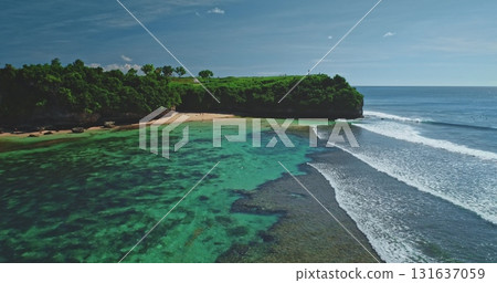 Turquoise waves are gently crashing on the shore of Dreamland Beach in Bali, Indonesia, creating a breathtaking view of a tropical paradise with lush green vegetation and crystal-clear waters Turquoise waves are gently crashing on the shore of Dreamland Beach in Bali, Indonesia, creating a breathtaking view of a tropical paradise with lush green vegetation and crystal-clear waters 131637059