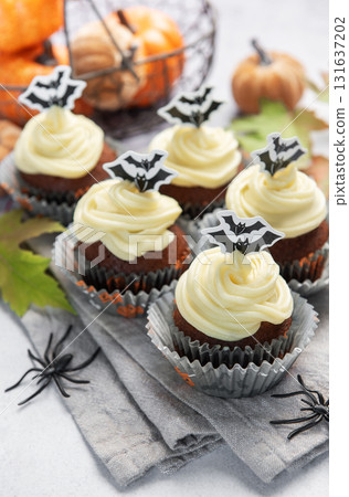 Halloween cupcakes with bat decoration and small pumpkins 131637202