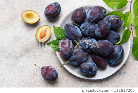 Fresh ripe plums, whole and halved on plate 131637205