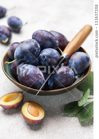 Fresh plums in bowl with knife on gray background 131637208