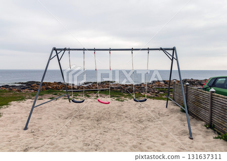Empty children's swing on the seashore on a cloudy day 131637311
